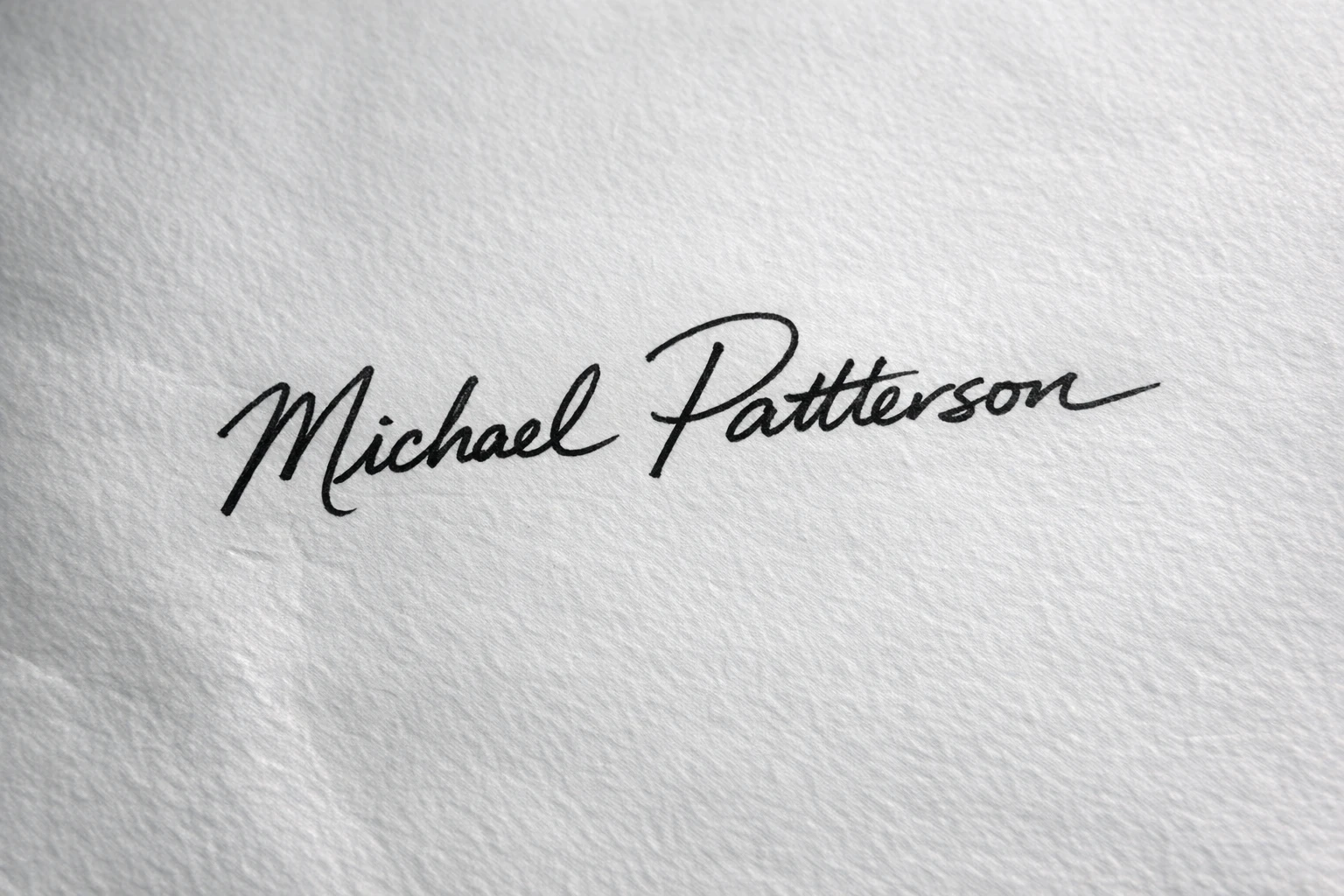 Handwritten signature on textured paper with shadows