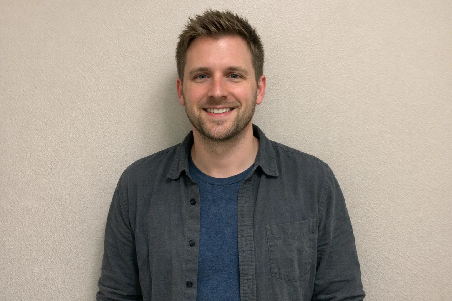 Professional standing against a plain wall